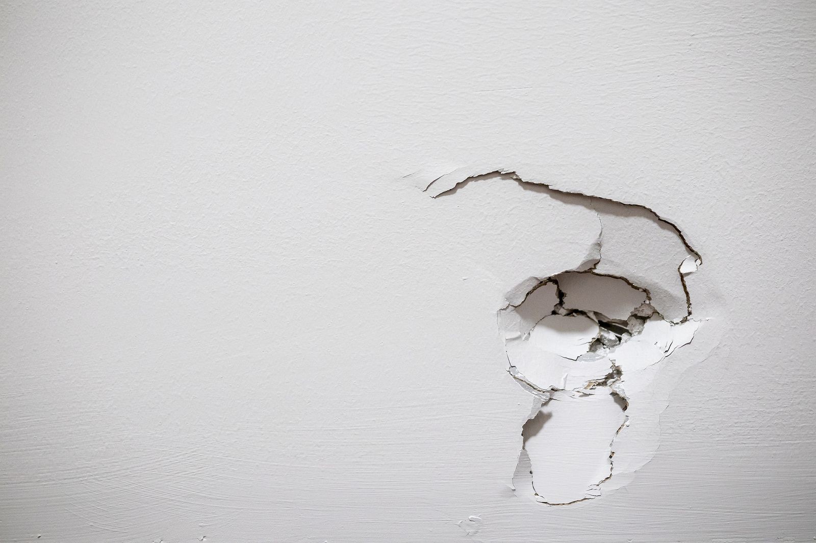 Damaged drywall with a hole before repair