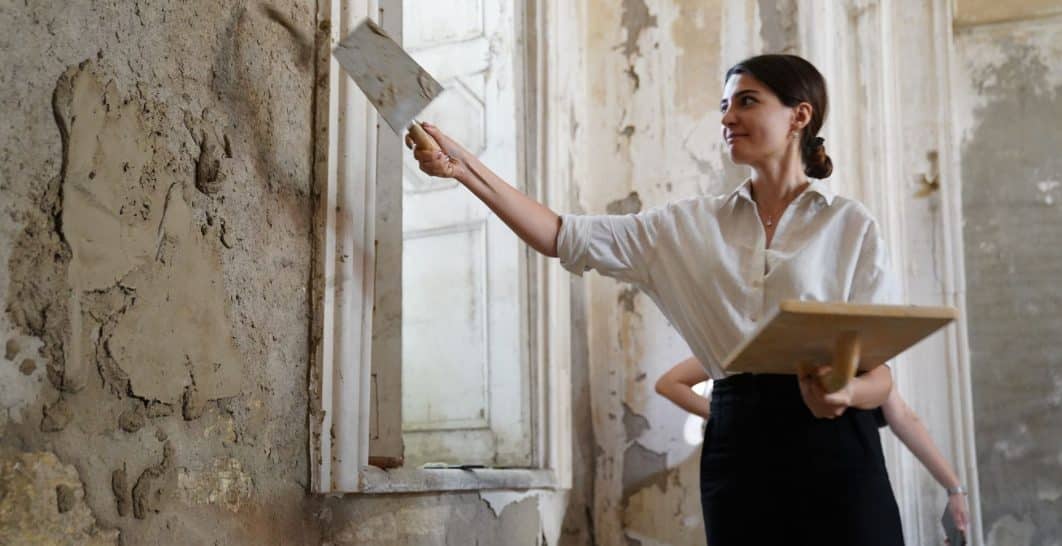 Finisher skim coating a drywall surface with a wide trowel