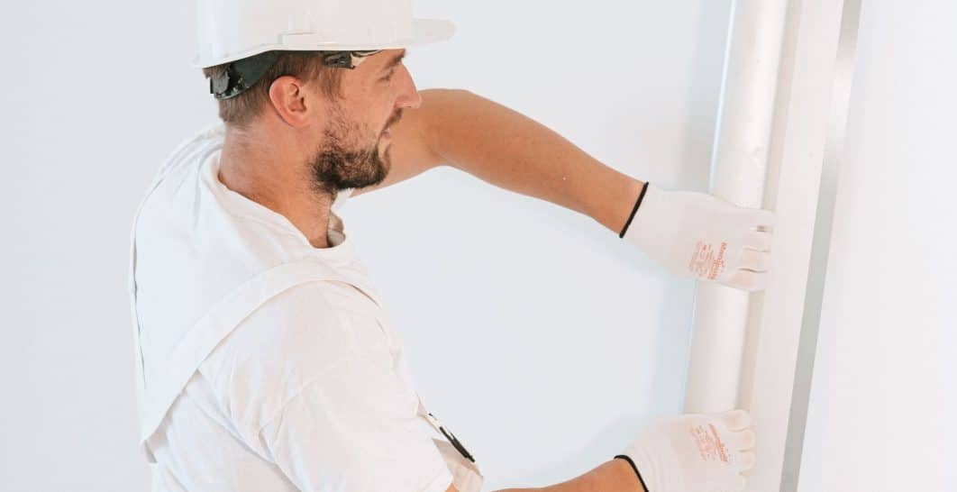 Contractor installing a sheet of drywall on an interior wall in a New Orleans home