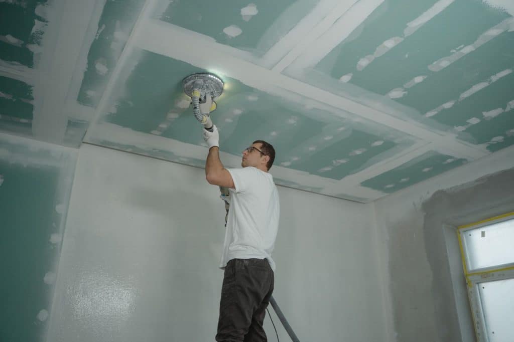 Drywall installer taping and mudding joints on a newly hung wall