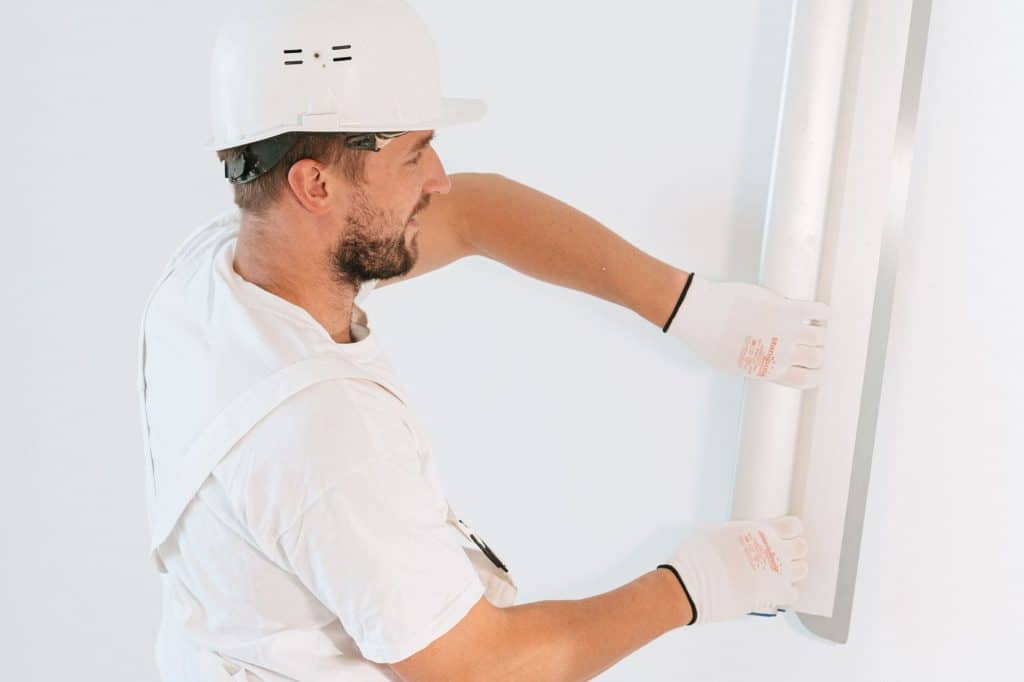 Drywall contractor hanging a gypsum panel during a home renovation