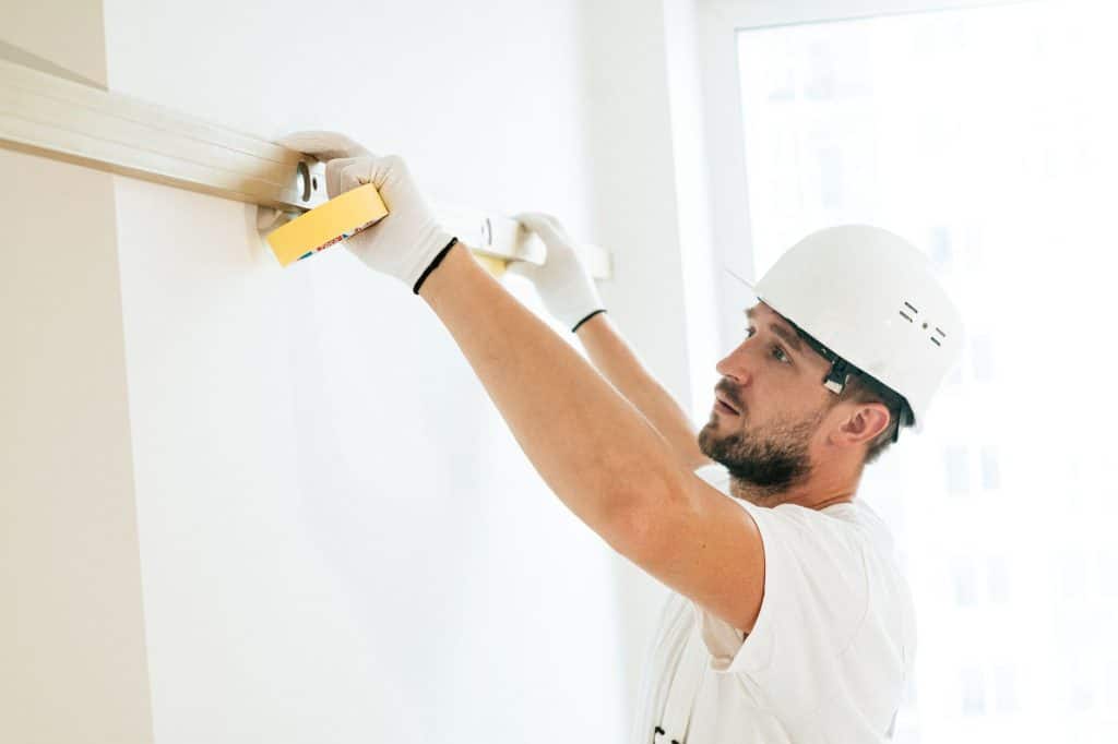 Contractor using a level to check wall accuracy before drywall installation