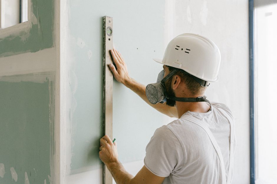 Wide shot of a wall showing the feathered, tapered edge of a finish coat under raking light, illustrating the smooth tra
