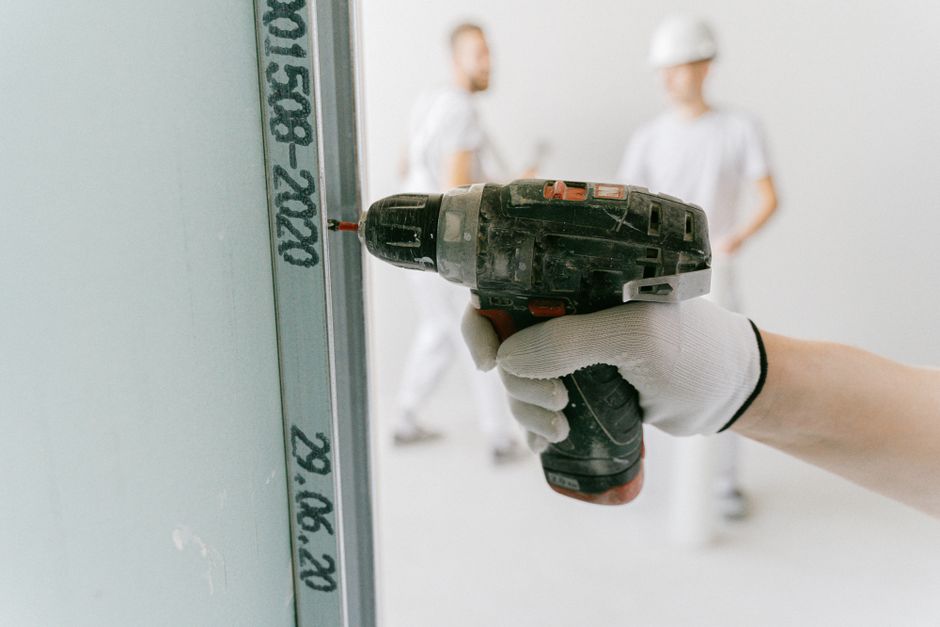 Close-up of a drywall screw set correctly in a shallow dimple, joint compound partially applied — represents "done right