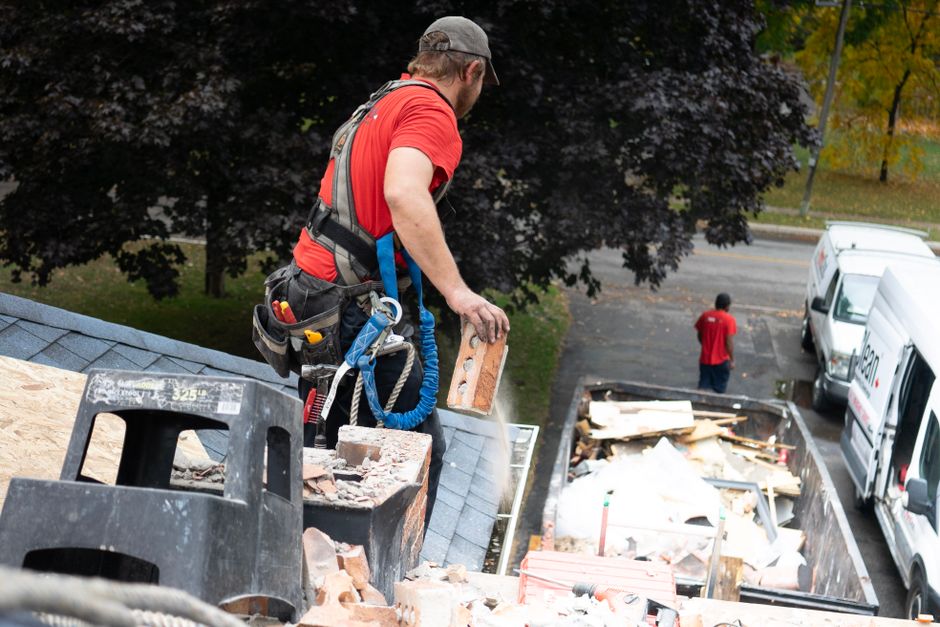 A dumpster or debris pile at a residential renovation site with stacked drywall sheets, taken from a slight elevated ang