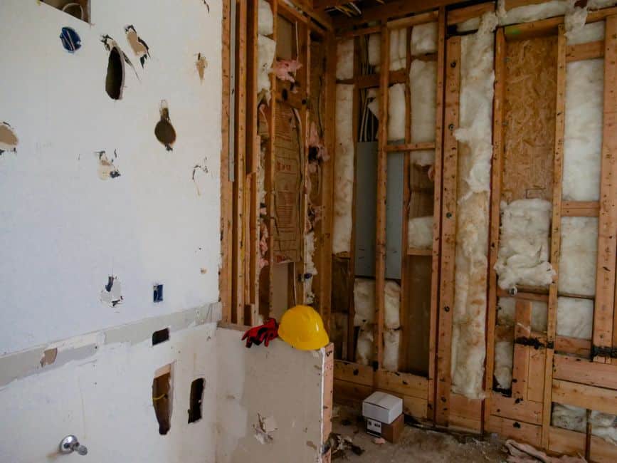 A close-up of a worker loading gypsum board scraps separately from general debris, illustrating the separation step desc
