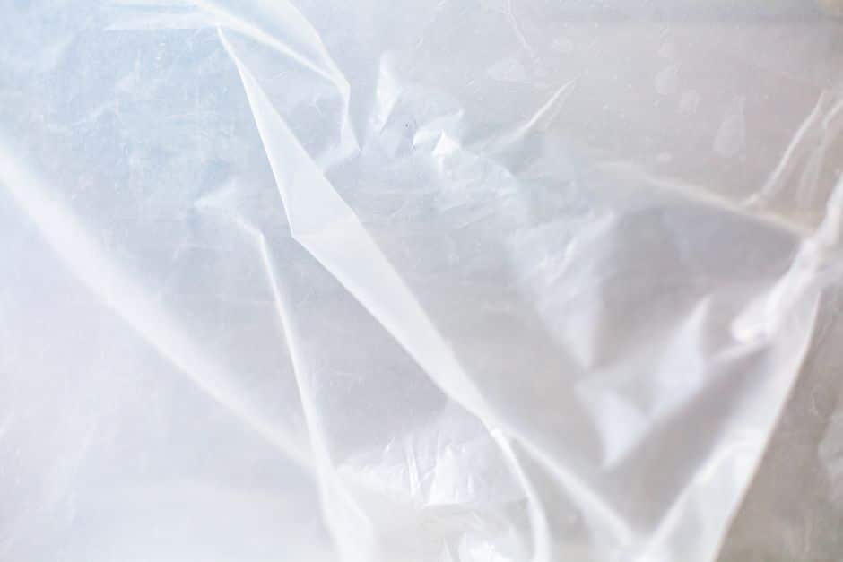 Interior renovation in progress inside an occupied-looking home, plastic sheeting taped over a doorway for dust containm